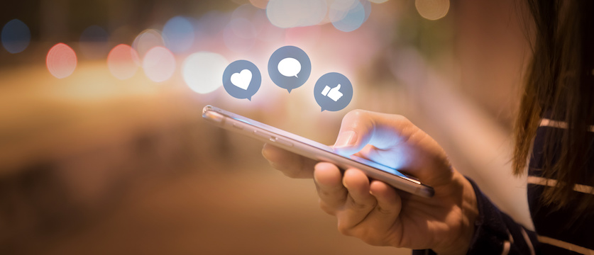 Woman hands using mobile smartphone in the street with icon social media and social network.